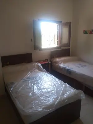 two beds covered in plastic in a room with a window at النبلاء جيست هاوس نوبيان اسوان in Aswan