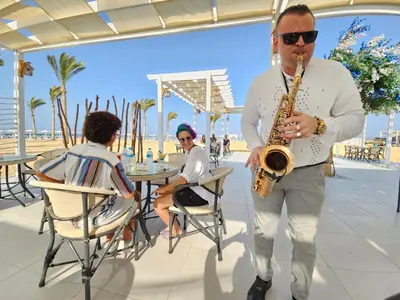 a man playing a saxophone on the beach at Casa Blue Resort in Marsa Alam City