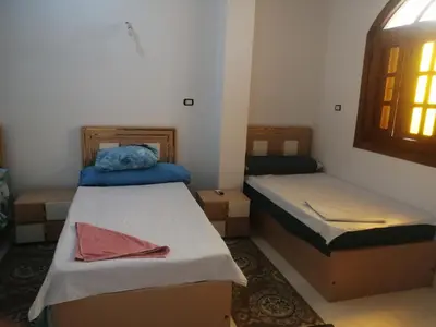 two beds in a small room with a window at Nubian Bride guest house in Aswan