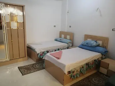 two twin beds in a room with a window at Nubian Bride guest house in Aswan