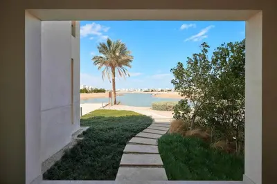a walkway leading to a beach with a palm tree at Ground floor two bedrooms in Joubal Lagoon with direct pool access and view in Hurghada