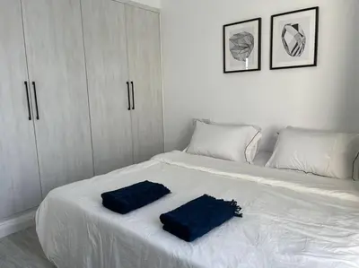 a white bed with two blue pillows on it at 2 bedroom with a private heated pool in Sholan2 in Hurghada