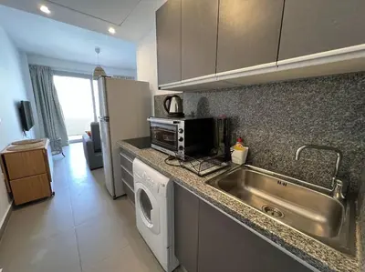 a kitchen with a sink and a washing machine at Ground floor one bedroom overlooking the pool. in Hurghada