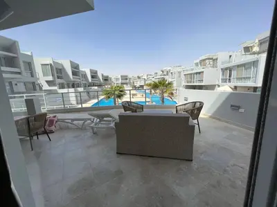 a balcony with a couch and chairs on a building at Ground floor one bedroom overlooking the pool. in Hurghada