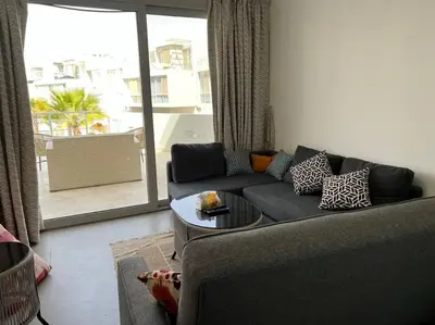 a living room with a couch and a table at Ground floor one bedroom overlooking the pool. in Hurghada