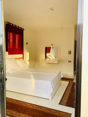 a bedroom with a large white bed with a red window at Villa Nile Rayan in Al Aqālitah