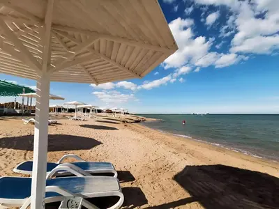a beach with chairs and an umbrella and the ocean at Selena Bay Luxury Resort - Premium Apartment with Private Beach in Hurghada