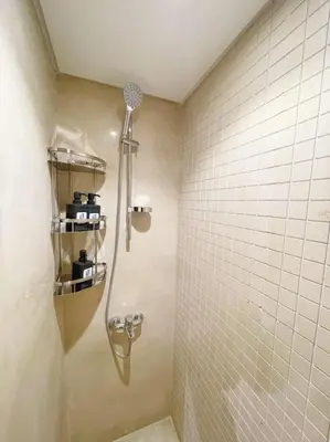 a shower in a bathroom with white tiles at Snazzy 1BDR w Rooftop Mangroovy Free Pool & Beach Access in Hurghada