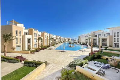 an apartment complex with a swimming pool and palm trees at Panoramic & Cushy 3BDR Mangroovy Free pool & Beach Access in Hurghada