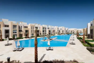 a swimming pool in a resort with a palm tree at Panoramic & Cushy 3BDR Mangroovy Free pool & Beach Access in Hurghada