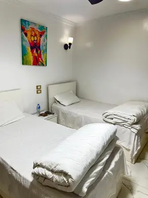 two beds in a room with a painting on the wall at White House in Aswan
