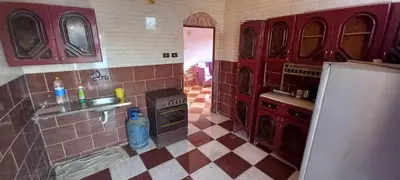 a kitchen with red cabinets and a tile floor at Gasser Holiday Home in Aswan