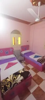 a room with two beds and a checkered floor at Gasser Holiday Home in Aswan