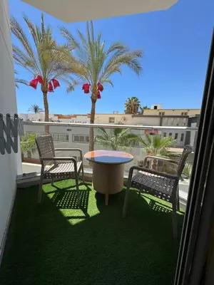 a balcony with two chairs and a table and palm trees at شقة احلامك علي البحر in Hurghada