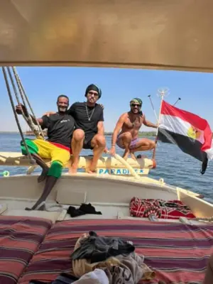 three men sitting on a boat in the water at NUBIAN MONALIZA guest house in Aswan
