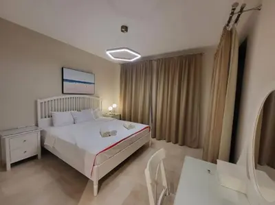 a bedroom with a white bed and a table and a desk at Mangroovy - 2BR La Blanca Pool View in Hurghada
