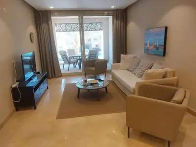 a living room with a couch and a tv and a table at Mangroovy - 2BR La Blanca Pool View in Hurghada