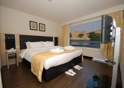 a hotel room with a bed and a large window at Cleopatra Nile Cruise in Luxor