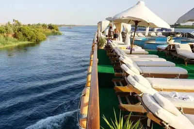 a row of chaise lounges on the side of a river at Ultra Nile Cruise 5 Star Luxor To Aswan in Luxor