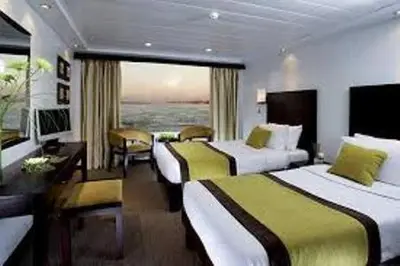 a hotel room with two beds and a large window at Ultra Nile Cruise 5 Star Luxor To Aswan in Luxor
