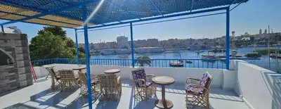a balcony with chairs and tables and a view of a river at La Terrace in Aswan