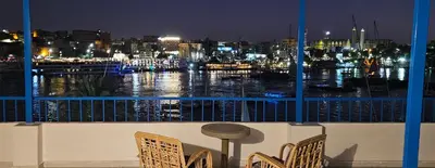 a balcony with a view of a harbor at night at La Terrace in Aswan