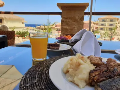 a table with a plate of food and a glass of beer at Amarina Jannah Resort & Aqua Park Marsa Alam in Coraya Bay