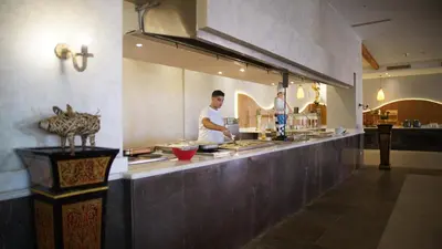 two men are preparing food in a restaurant kitchen at Amarina Jannah Resort & Aqua Park Marsa Alam in Coraya Bay