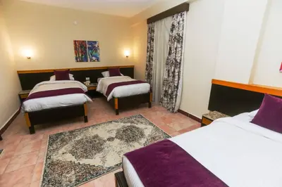 a hotel room with three beds and a rug at Jawhara Inn Hotel - فندق الجوهرة سفاجا in Hurghada