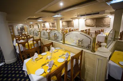 a dining room with tables and chairs with yellow table cloth at ToBadaa - Nile cruise all inclusive from Aswan or Luxor 4 Days & 7 days in Aswan