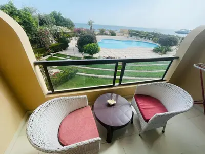 a balcony with two chairs and a table and a pool at Navy Chalets 107 in Hurghada
