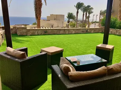 a view of a lawn with chairs and a table at Apartment Azzura Sahl Hasheesh with private garden in Hurghada