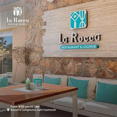 a table and a couch with a sign on a wall at Apartment Azzura Sahl Hasheesh with private garden in Hurghada
