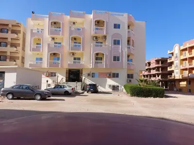 a large building with cars parked in a parking lot at Nice Studio in Elegant Compound Intercontinental Area in Hurghada