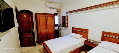 a bedroom with two beds and a wooden cabinet at Moon fourteen2 in Luxor