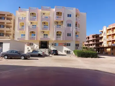 a large building with cars parked in a parking lot at Cozy/Comfy Studio at Intercontinental Area in Hurghada