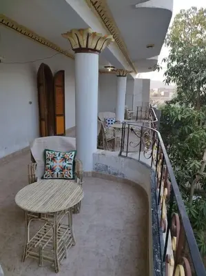 a porch with a chair and a table on a balcony at Gabawy Garden, Privatzimmer mit zwei Einzelbetten in Luxor